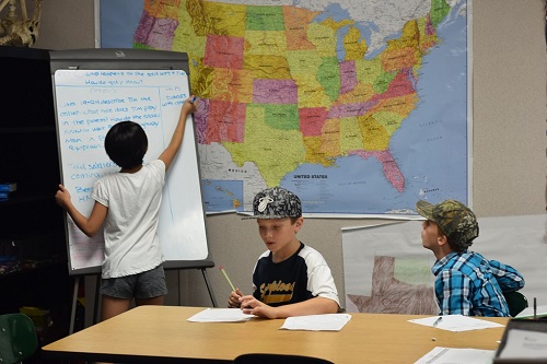 student writing on board while others offer advice student writing on board while others offer advice